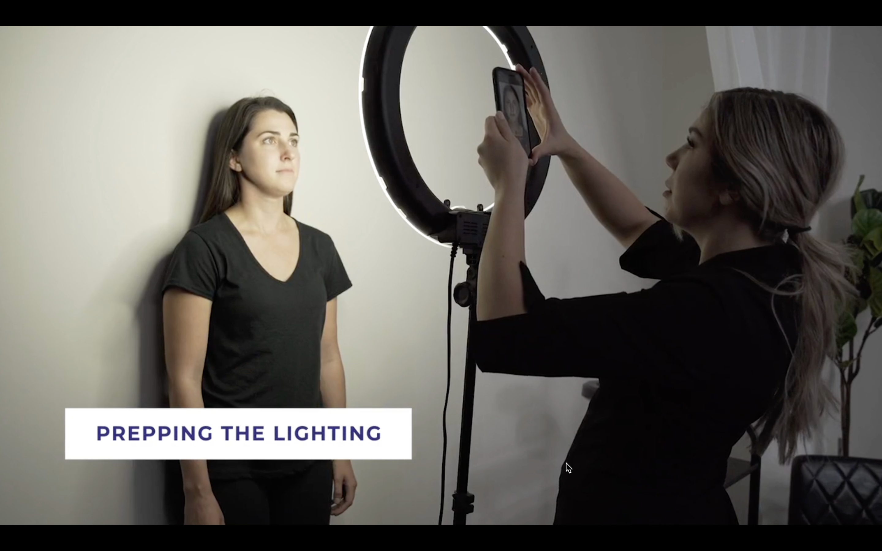 woman taking photo of client using a ring light and phone